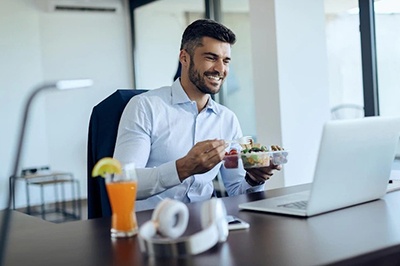 happy businessman using laptop while having lunch break at office